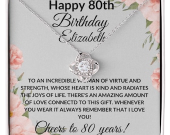 May include: A silver necklace with a knot pendant and clear crystals. The necklace comes in a gift box with a floral design and the text "Happy 80th Birthday Elizabeth. To an incredible woman of virtue and strength, whose heart is kind and radiates the joys of life. There's an amazing amount of love connected to this gift. Whenever you wear it always remember that I love you! Cheers to 80 years!"
