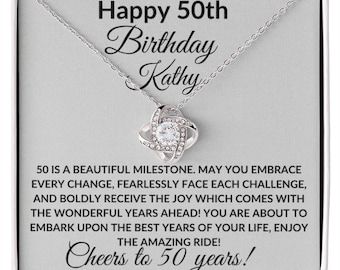 May include: A silver necklace with a clear crystal knot pendant comes in a gift box with a message that reads "Happy 50th Birthday Kathy 50 is a beautiful milestone. May you embrace every change, fearlessly face each challenge, and boldly receive the joy which comes with the wonderful years ahead! You are about to embark upon the best years of your life, enjoy the amazing ride! Cheers to 50 years!"