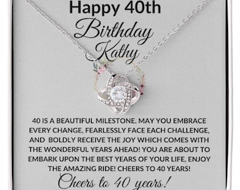 May include: A silver necklace with a knot pendant featuring a clear crystal in a gift box. The box has a message that reads "Happy 40th Birthday Kathy 40 is a beautiful milestone. May you embrace every change, fearlessly face each challenge, and boldly receive the joy which comes with the wonderful years ahead! You are about to embark upon the best years of your life, enjoy the amazing ride! Cheers to 40 years! Cheers to 40 years!"