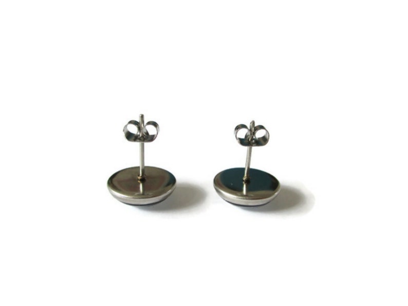 May include: A pair of silver stud earrings with a round, dark blue cabochon stone in the center.