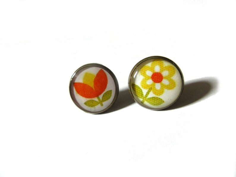 May include: A pair of earrings with a flower design. One earring features a yellow flower with a red center, and the other earring features a red flower with a yellow center.