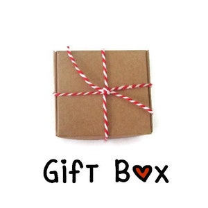 May include: A brown cardboard gift box tied with red and white twine. The box is sitting on a white background. The text "Gift Box" is written below the box with a red heart symbol.