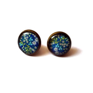 May include: A pair of bronze stud earrings with a blue background and a floral pattern in white, yellow, and blue.