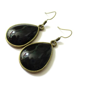 Peut inclure: Une paire de boucles d'oreilles en forme de goutte avec des pierres en verre noir serties dans un métal doré.