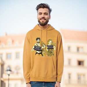 Könnte beinhalten: Ein senfgelber Hoodie mit einem Grafikdruck von zwei Personen, die Fahndungsfotos halten. Der Text auf den Fahndungsfotos lautet "ARRESTED POLICE DEPT" und "SUSPECTED"