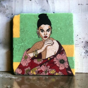 Könnte beinhalten: Eine Frau mit dunklen Haaren und einem roten und rosa floral gemusterten Schal sitzt mit ineinander verschränkten Händen vor sich. Der Hintergrund ist ein grünes und gelbes Marmormuster.