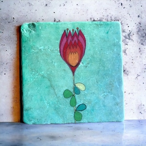 Peut inclure: Un carreau carré turquoise avec une fleur stylisée rouge, orange et jaune avec des feuilles vertes peintes dessus.