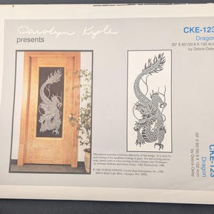 May include: A printed pattern for a dragon design, labeled CKE-123, with dimensions of 20 inches by 60 inches (50.8 cm x 152.4 cm). The design features a detailed dragon silhouette. The text "Carolyn Kyle presents" is at the top.