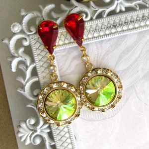 May include: A pair of dangle earrings with a green iridescent crystal surrounded by clear rhinestones and a red teardrop crystal above.