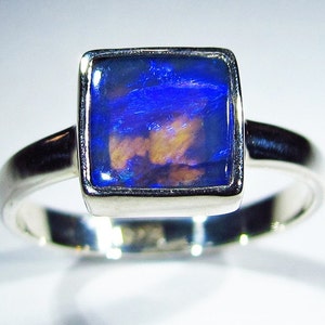 May include: A silver ring with a square blue opal gemstone set in a silver bezel.