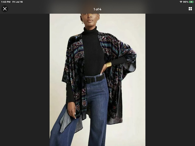 Puede incluir: Un kimono de terciopelo negro con un estampado geom&eacute;trico colorido. El kimono tiene mangas largas y una silueta ancha y fluida. Se lleva sobre una camisa de cuello alto negra y unos vaqueros azules.