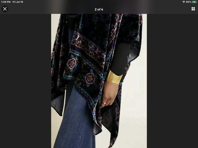 Puede incluir: Un kimono de terciopelo negro con un estampado floral colorido. El kimono tiene una silueta larga y fluida y es perfecto para superponer sobre un atuendo sencillo.