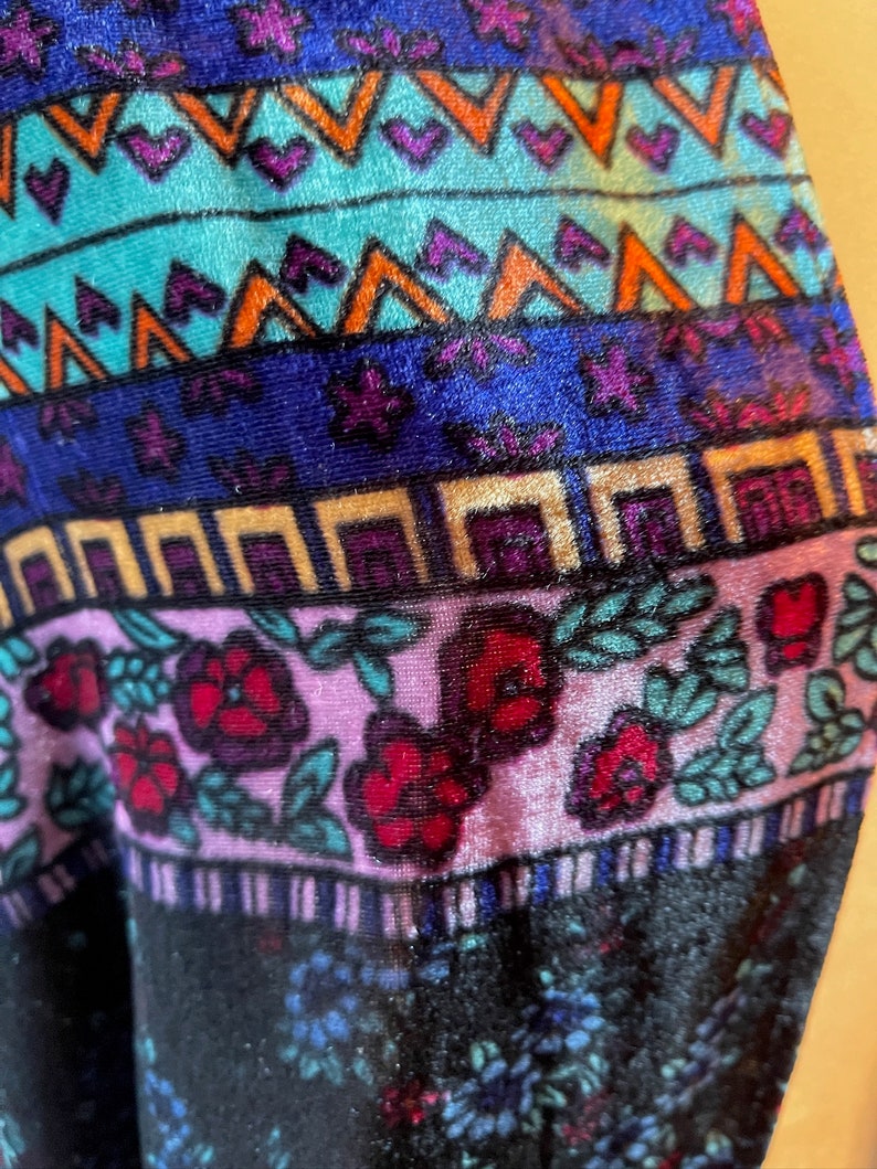 Puede incluir: Primer plano de una tela colorida con un patr&oacute;n geom&eacute;trico y dise&ntilde;o floral. La tela es de terciopelo y tiene un tacto suave y lujoso.