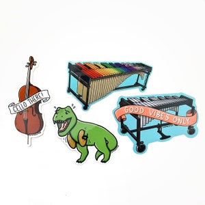 K&ouml;nnte beinhalten: Vier bunte Aufkleber mit einem Cello, einem Dinosaurier, einem Xylophon und einem Vibraphon. Der Cello-Aufkleber tr&auml;gt den Text "Cello There!" Der Dinosaurier-Aufkleber zeigt einen gr&uuml;nen Dinosaurier mit roter Zunge. Der Xylophon-Aufkleber zeigt ein Regenbogen-Xylophon mit einem Holzrahmen. Der Vibraphon-Aufkleber zeigt ein silbernes Vibraphon mit einem blauen Rahmen und dem Text "Good Vibes Only".