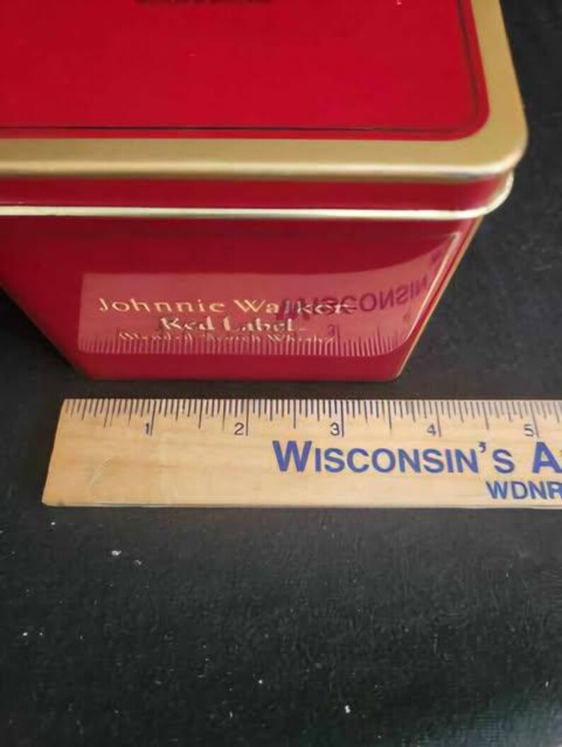 May include: Red tin box with a gold trim and the words "Johnnie Walker Red Label" printed on the side.