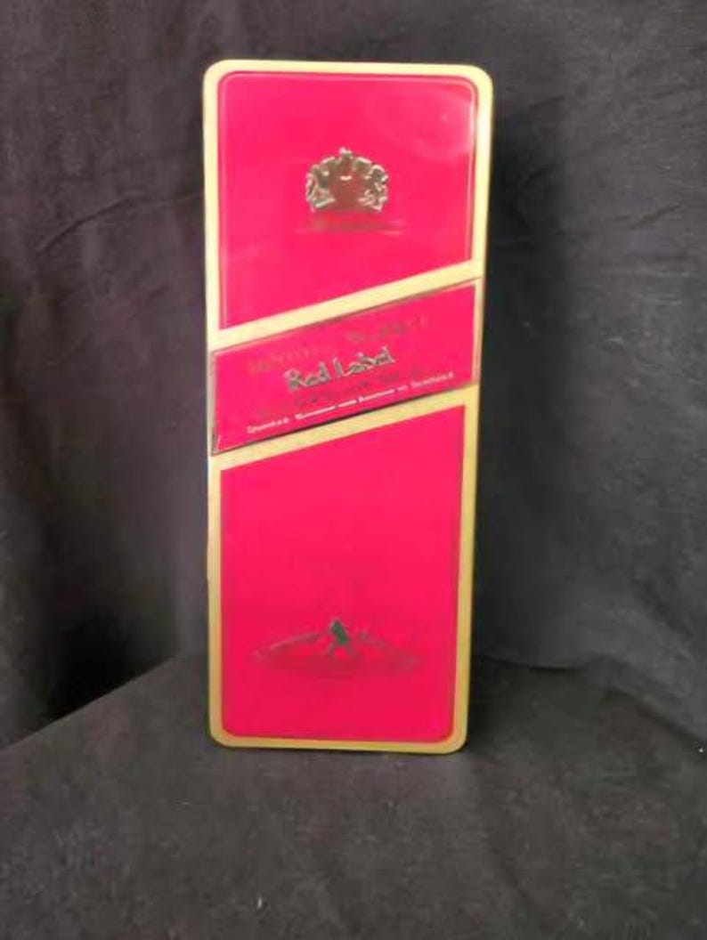 May include: A red and gold tin with the words "Johnnie Walker Red Label" and a crest on the front.