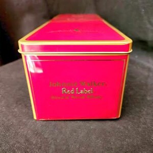 May include: A red and gold tin box with the words "Johnnie Walker Red Label Blended Scotch Whisky" printed on the front.