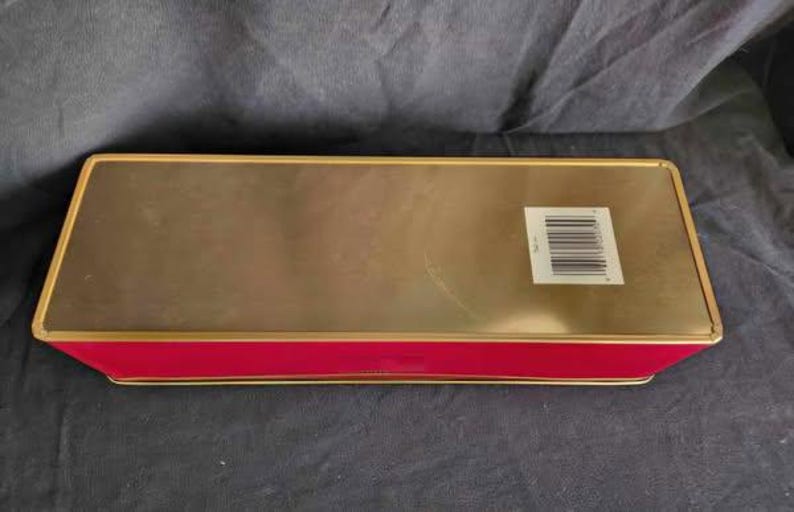 May include: A gold and red rectangular tin box with a barcode on the side.