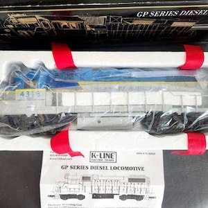 May include: A model GP Series Diesel Locomotive, packaged in a box with red ribbon. The locomotive is blue, yellow, and gray, with the number 4316 on the side. The box also contains a K-Line Electric Trains instruction sheet.