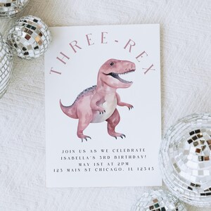 以下が含まれることがあります： ピンク色の水彩恐竜のイラストと「THREE-REX」の文字が入った誕生日招待状。イザベラの3歳の誕生日のお祝いの詳細が含まれています。銀色のディスコボールが、白いテクスチャのある表面の招待状を囲んでいます。