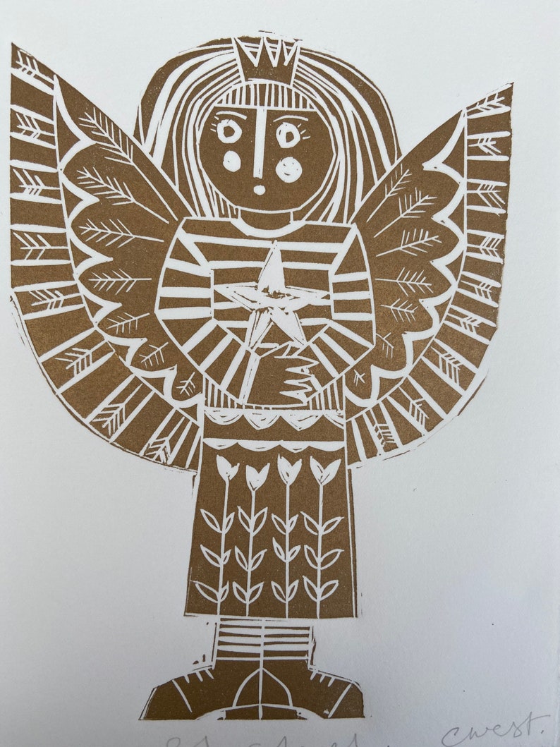 May include: A brown linocut print of an angel with a crown, wings, and a star. The angel is wearing a striped dress and has a simple face. The print is signed 'crest' in the bottom right corner.