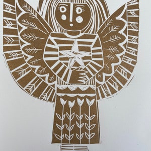May include: A brown linocut print of an angel holding a star. The angel has a crown, long hair, and a striped dress. The angel's wings are large and feathery. The angel is standing on a white background.