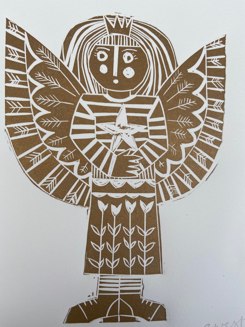 May include: A brown linocut print of an angel holding a star. The angel has a crown, long hair, and a striped dress. The angel's wings are large and feathery. The angel is standing on a white background.