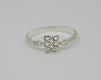 May include: A silver ring featuring a Celtic knot design. The ring has a thin band and a detailed knot centerpiece. The ring is displayed on a white background, highlighting its intricate design and metallic sheen.