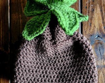 Puede incluir: Un gorro de punto marrón con una flor de punto verde en la parte superior.