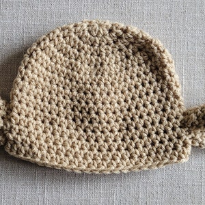 May include: A crocheted baby hat with two floppy ears, in a light brown color.