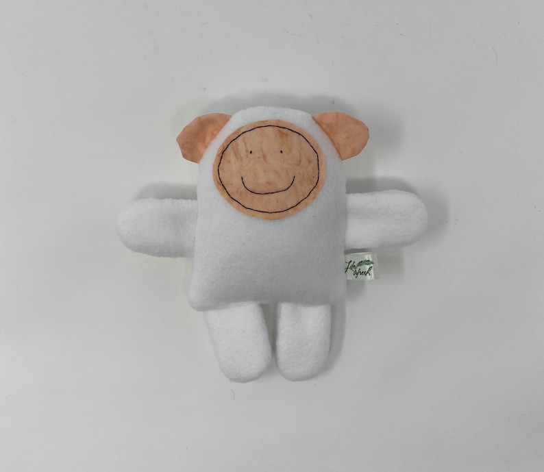 May include: White plush toy shaped like a sheep with a brown felt face and a smiling mouth. The toy has a small tag that says "Love you"