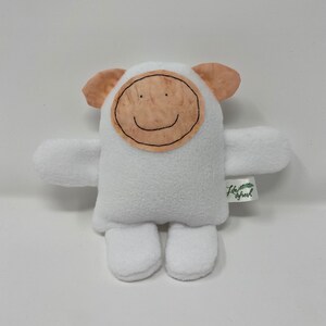 May include: White plush toy with a brown felt face and a smiling mouth. The toy has small ears and arms and is sitting on a white background. The toy has a tag that says "Little Sprout".
