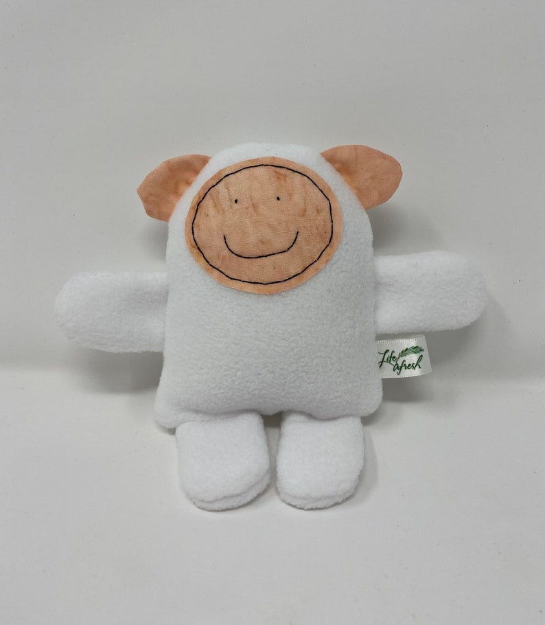 May include: White plush toy with a brown felt face and a smiling mouth. The toy has small ears and arms and is sitting on a white background. The toy has a tag that says "Little Sprout".