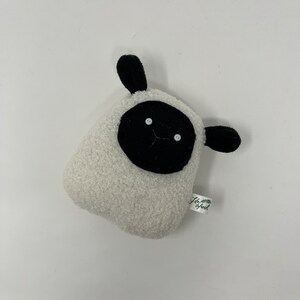 Pode incluir: Brinquedo de pel&uacute;cia branco em forma de ovelha com orelhas pretas e um rosto preto. O brinquedo tem dois olhos de bot&atilde;o branco e uma pequena boca preta costurada. O brinquedo tem uma etiqueta verde que diz "Life is Fresh".