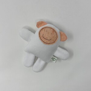 May include: White plush toy shaped like a sheep with a brown felt face and a smiling mouth. The toy has a small green tag that says "Happy Owl".