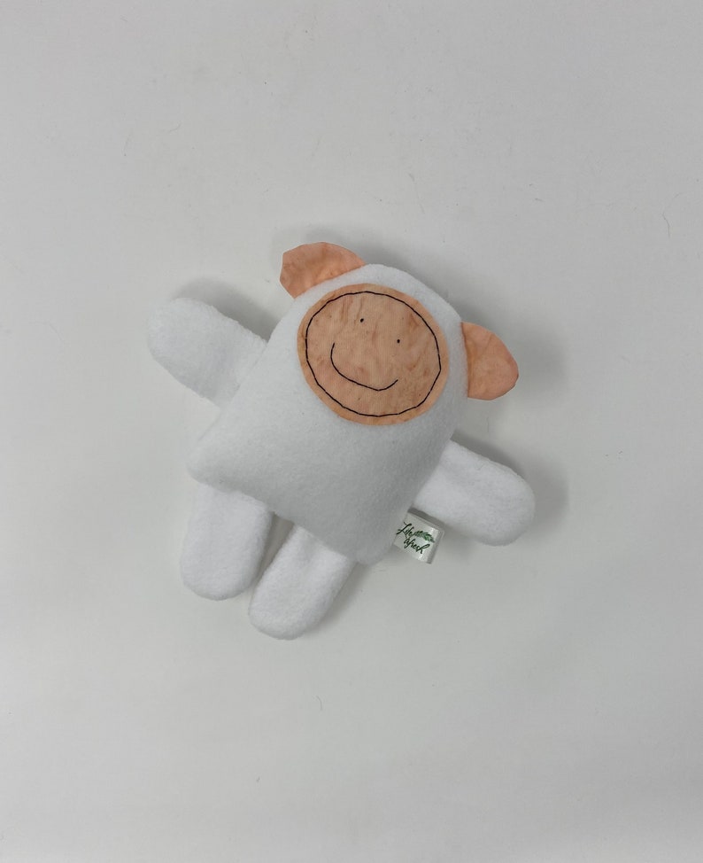 May include: White plush toy shaped like a sheep with a brown felt face and a smiling mouth. The toy has a small green tag that says "Happy Owl".