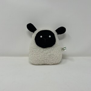 Pode incluir: Brinquedo de pel&uacute;cia branco em forma de ovelha com orelhas, rosto e olhos pretos. O brinquedo tem uma pequena etiqueta que diz "Happy Owl".