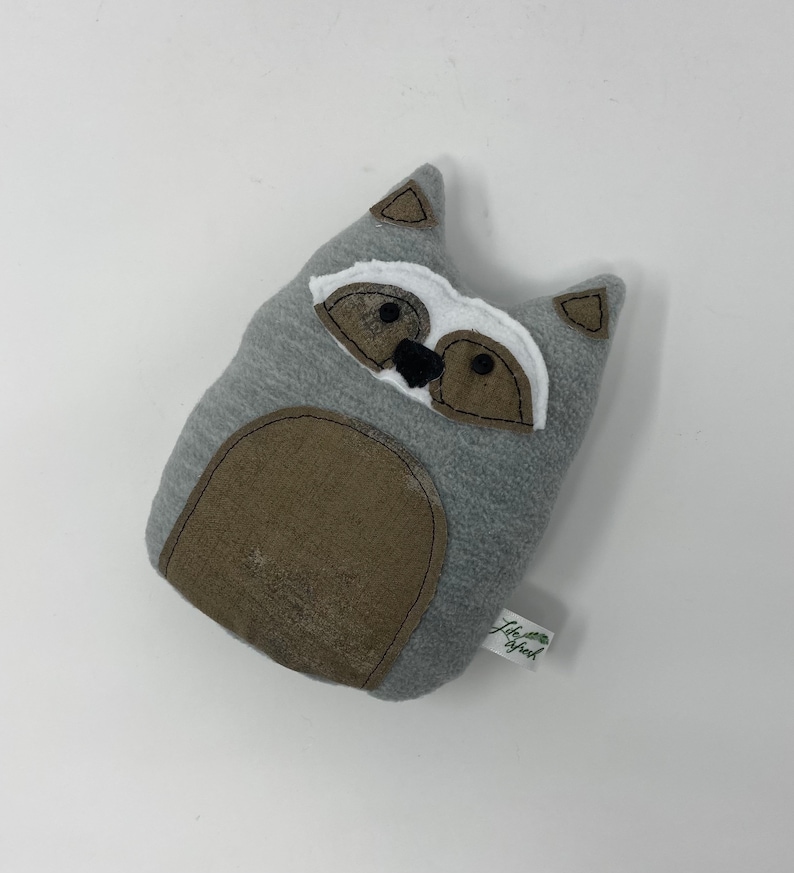 May include: Gray plush raccoon stuffed animal with a white face and black eyes. The stuffed animal has a brown belly and a tag that says "Little Sprout".
