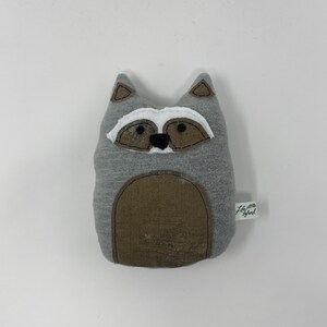 May include: Gray plush raccoon stuffed animal with a brown belly and black eyes. The stuffed animal has a white patch on its face and a small green tag that says "Little Sprout".