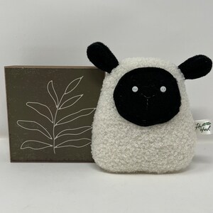 Pode incluir: Brinquedo de pel&uacute;cia branco em forma de ovelha com orelhas, rosto e nariz pretos. A ovelha tem dois olhos de bot&atilde;o brancos. O brinquedo tem uma pequena etiqueta que diz "Little Sheep".