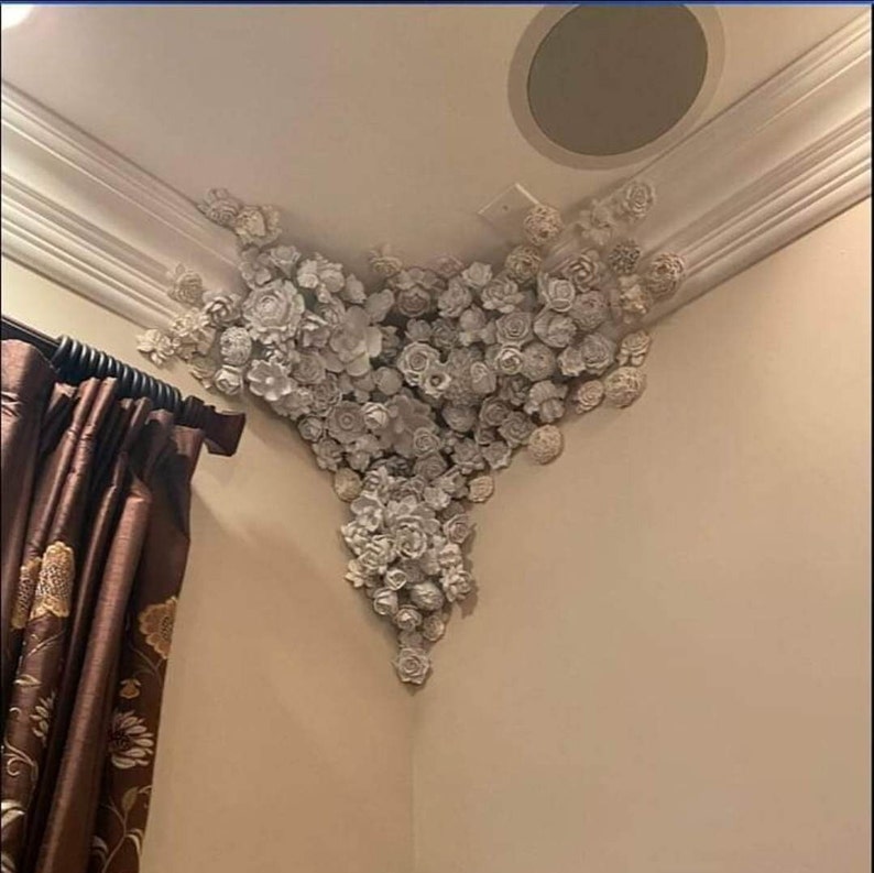 Puede incluir: Una esquina de techo blanco decorada con un grupo de flores de papel blancas.