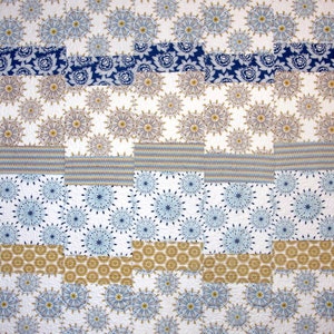 May include: A quilt with a patchwork design featuring various blue and brown patterns. The quilt is made up of squares and rectangles of different sizes and colors. The quilt is made of fabric with a white background and a variety of blue and brown patterns.