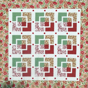 May include: A quilt with a white background and a repeating pattern of green and red squares. The squares are made up of smaller squares with floral patterns. The quilt is bordered with a floral pattern.