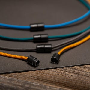 Back view of Paracord ID Lanyards showing durable breakaway safety clasps and color-matched cords in Goldenrod, Charcoal Grey, Teal, and Caribbean Blue — lightweight and non-metal for MRI environments.
