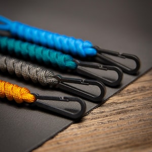 Close-up angled view of Paracord ID Lanyards showing black non-ferrous clips and braided paracord detail, emphasizing the rugged design of the MRI-safe badge holders.