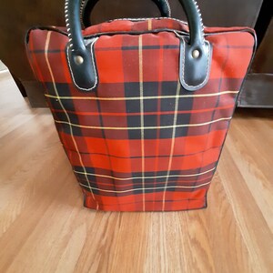 May include: Red and black plaid tote bag with black leather handles and brass accents.