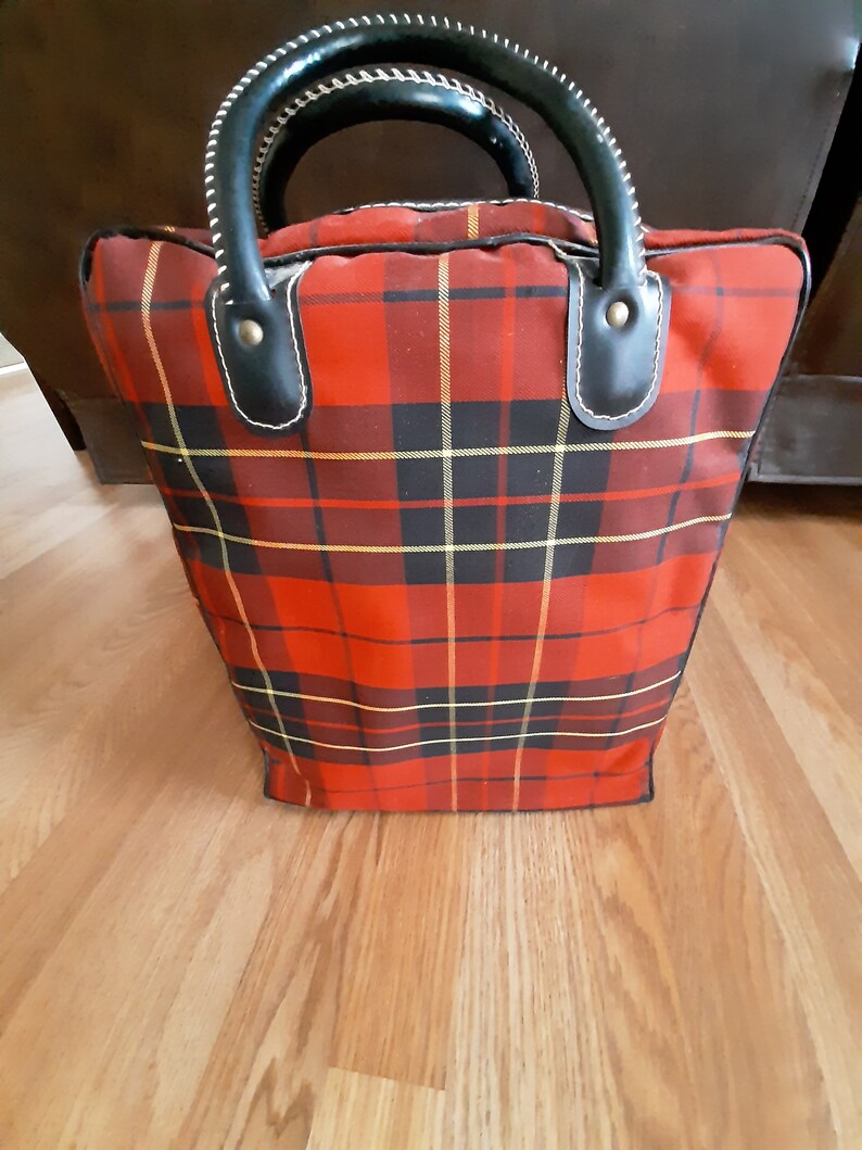 May include: Red and black plaid tote bag with black leather handles and brass accents.