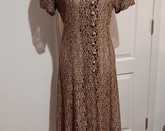 May include: A brown and black lace dress with a V-neckline and short sleeves. The dress has a button-up front and a flowy skirt.