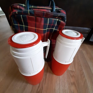 May include: Two red and white insulated thermos bottles with a red plaid travel bag. The thermos bottles have a white lid with a red band and a red base.