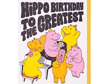 Op de afbeelding: Een felicitatiekaart met een kleurrijke illustratie van nijlpaarden die een verjaardag vieren. De kaart heeft de tekst "Hippo Birthday to the Greatest".